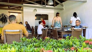 Un espace extérieur aménagé pour les repas, avec des meubles en osier et une structure de toit abritée.