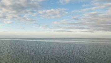 Ruhiges Meer mit einer entfernten Küste und einem teilweise bewölkten Himmel.