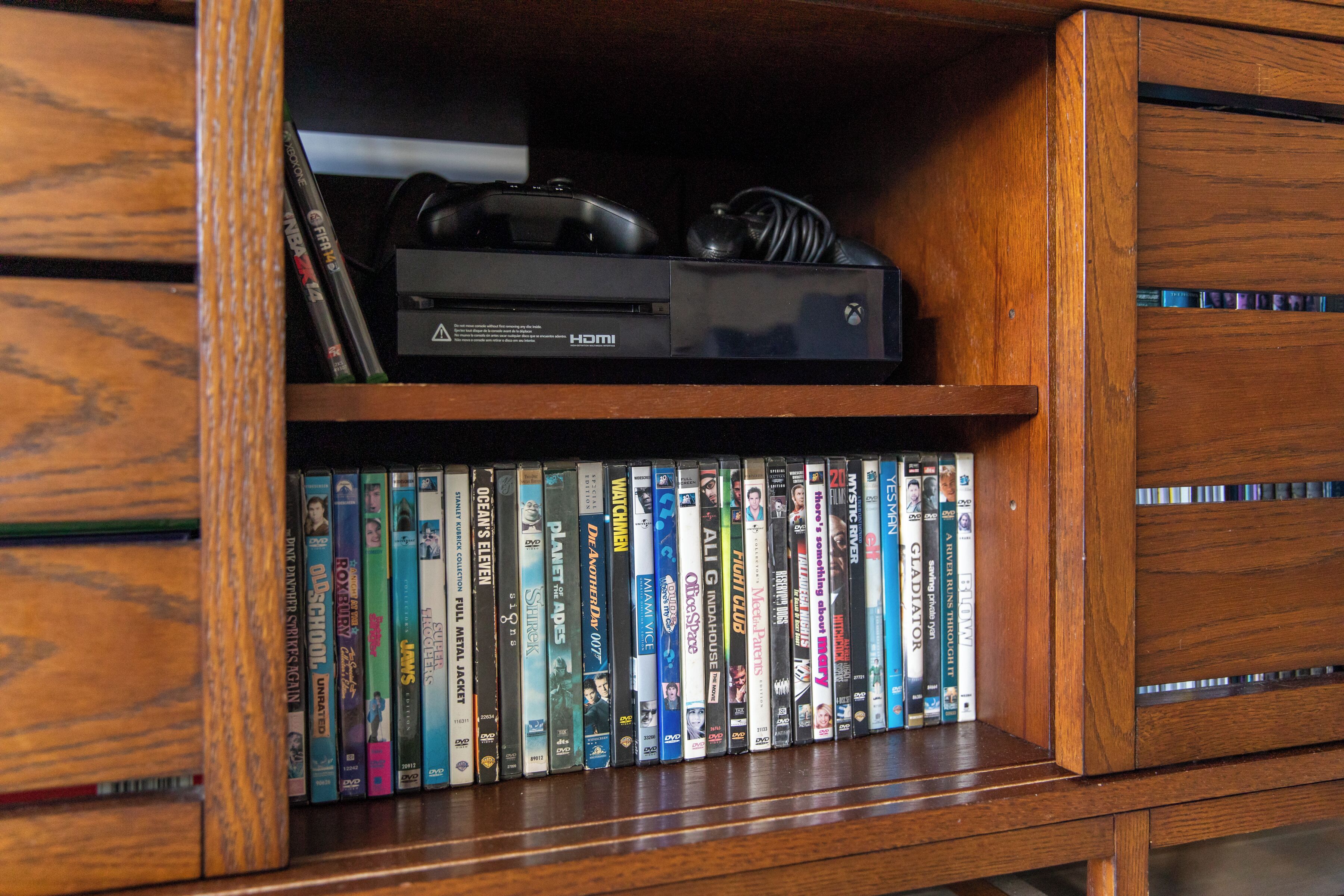 Une étagère en bois où sont rangés des jeux vidéo et des DVD.