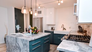 A modern kitchen with a marble island, stainless steel appliances, and teal cabinetry. - Beachfront Villas at Crystal Cove (St. Thomas)