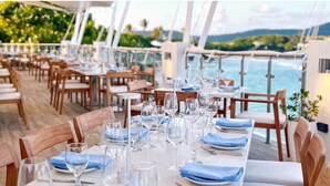 A restaurant with tables set for dining, overlooking a body of water. - Beachfront Villas at Crystal Cove (St. Thomas)