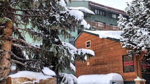 A wooden cabin labeled "Copper Junction" with snow-covered trees and a building in the background.