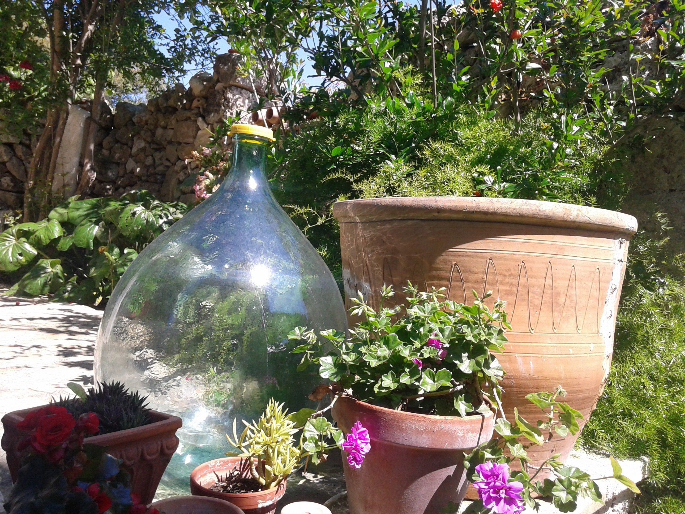 Un jardin agrémenté de différentes plantes en pot et d’un grand pot en terre cuite.