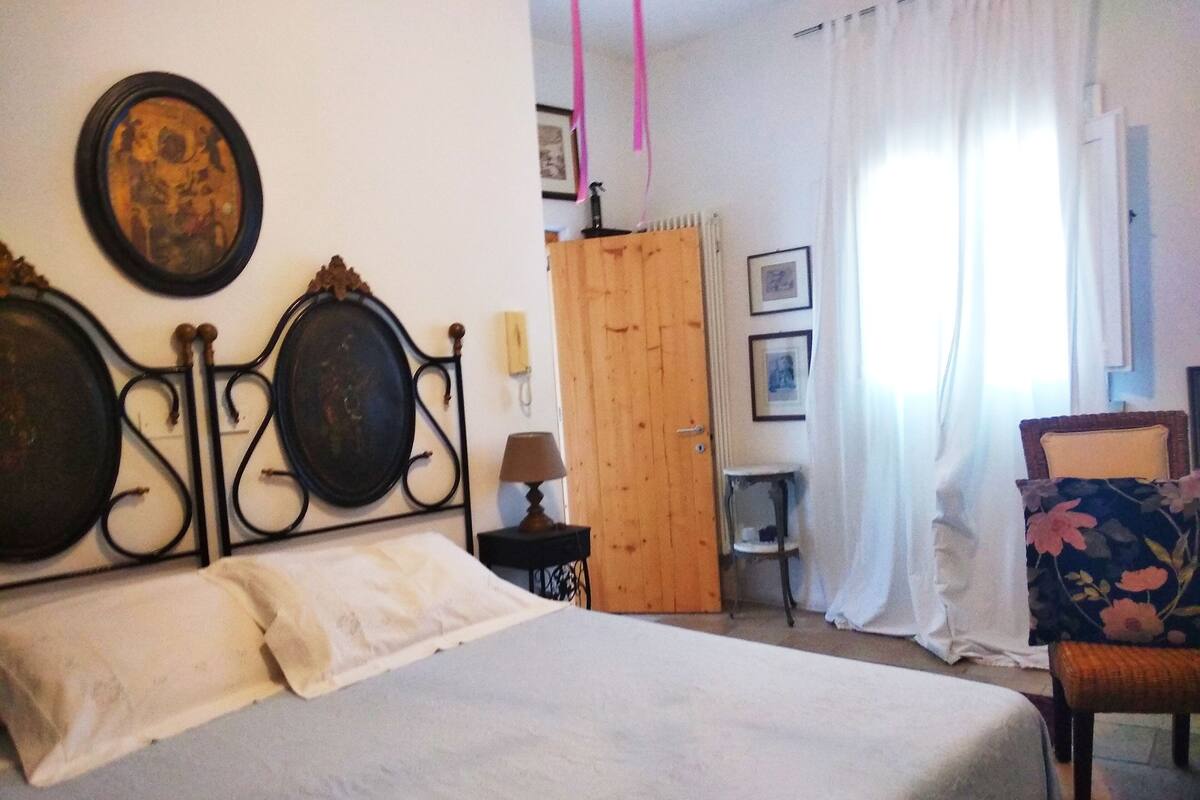 Un dormitorio con cama, un armario de madera, una silla y una mesita.