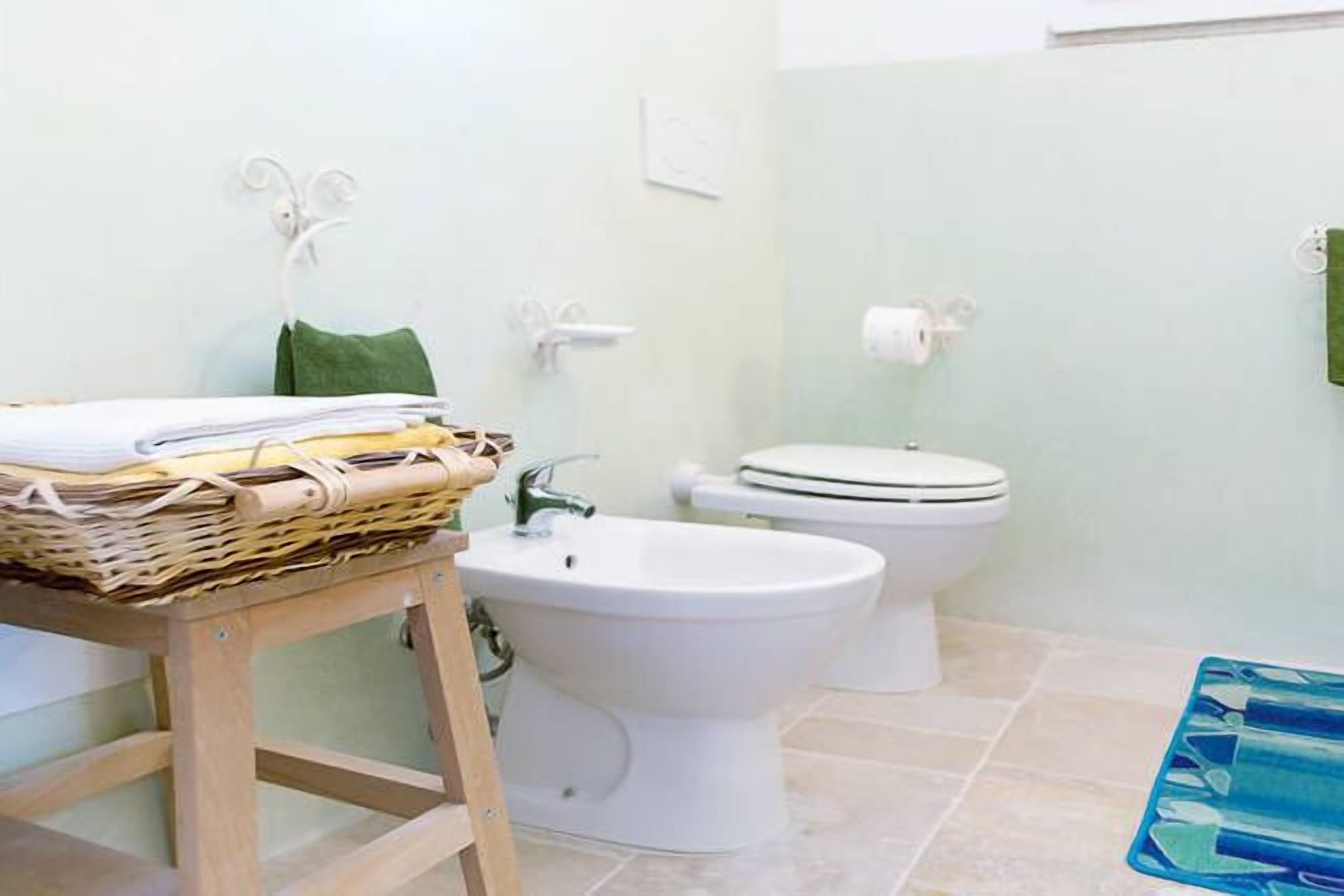 Ein Badezimmer mit Bidet, Toilette und einem Holztisch mit Handtüchern.