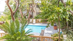 A pool area with a wooden deck, lounge chairs, and potted plants. - Villa Marina Vista (St. Thomas)