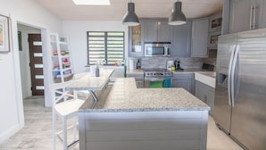 A modern kitchen with granite countertops, stainless steel appliances, and pendant lighting. - Villa Marina Vista (St. Thomas)
