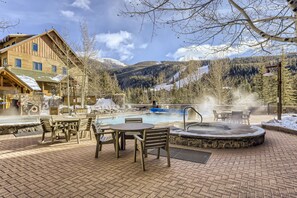 Un chalet en bois doté d’un bain à remous et d’un espace extérieur aménagé, entouré de montagnes enneigées.