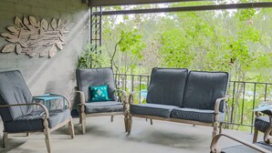 A covered outdoor seating area with wicker furniture and a decorative wall. - Romantic Inn suite with Air Jet Jacuzzi & private bath (Logan)