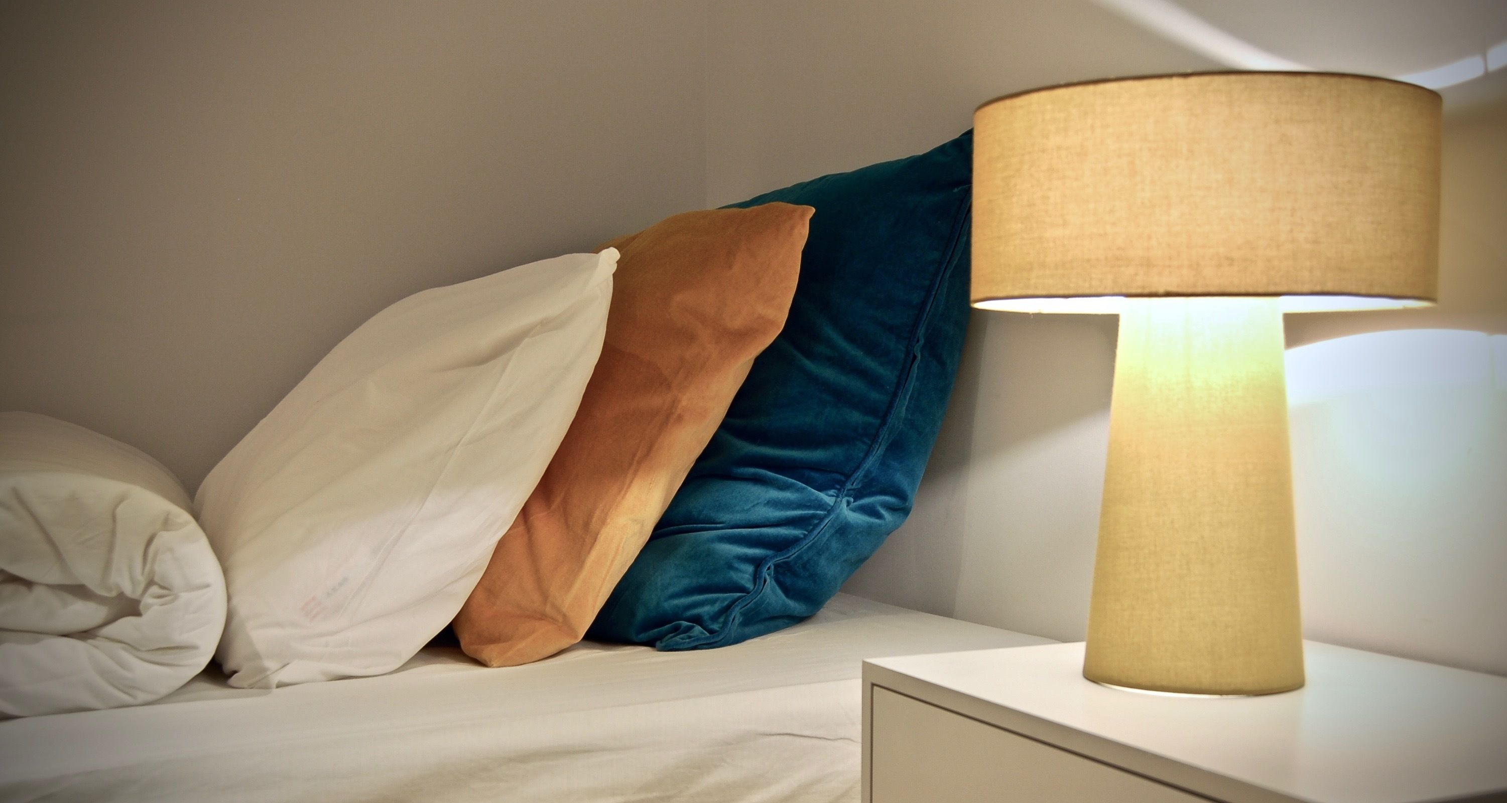 Una cama bien hecha con almohadas y una lámpara de noche.