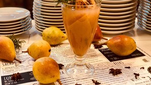 Ein Tisch mit einem Getränk in einem Glas, verziert mit Rosmarin, umgeben von Tellern und Zitronen.