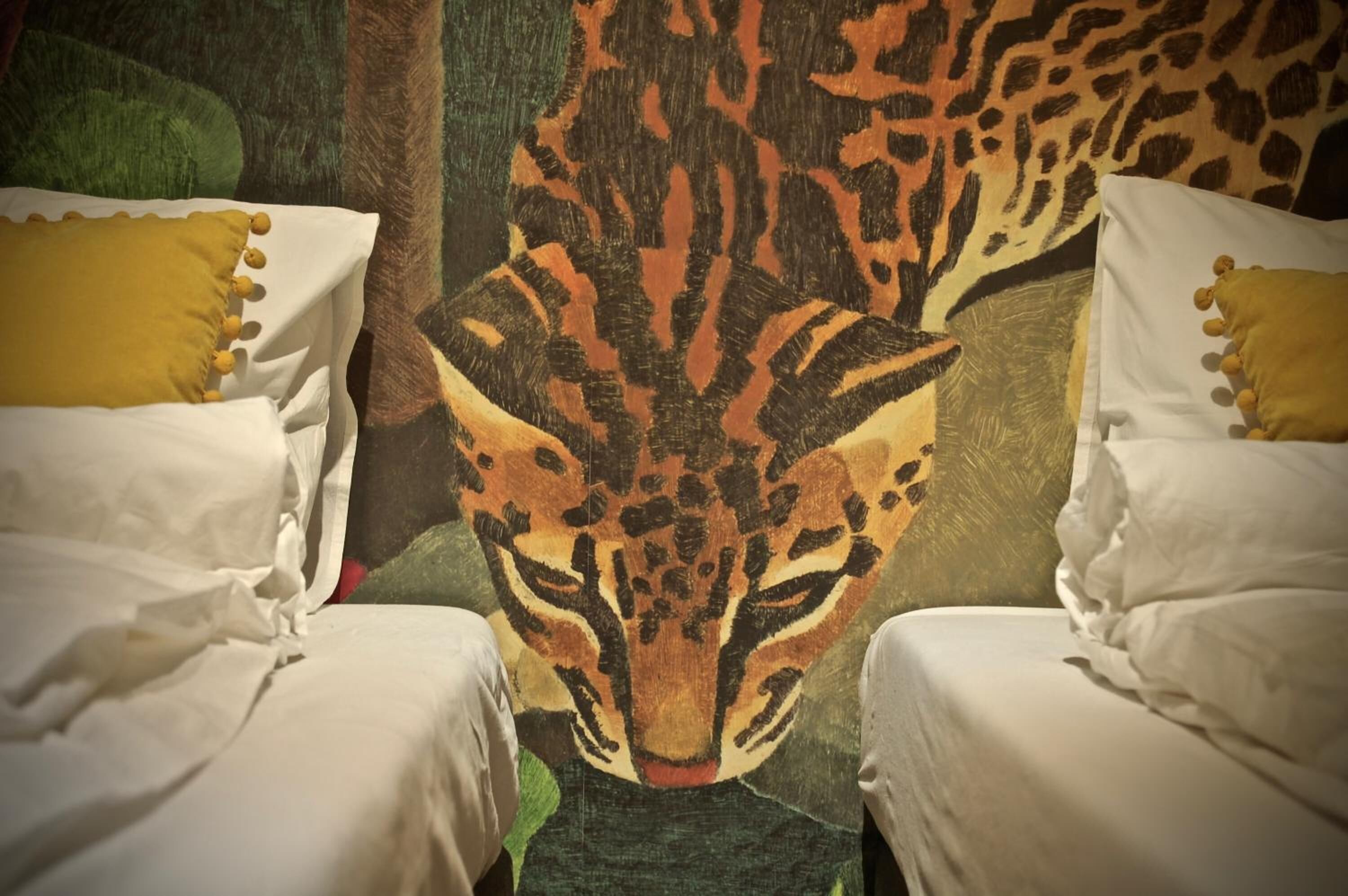 Quarto com duas camas, cada uma com roupa de cama branca e almofadas amarelas.