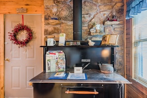 Cozy space with a traditional cooking area, wooden door, and stone wall, perfect for relaxation.