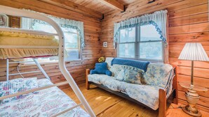 Een houten chalet van binnen met een stapelbed, een bank en een lamp.