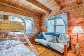 Cozy cabin-style room with a bunk bed, sofa, and table lamp.