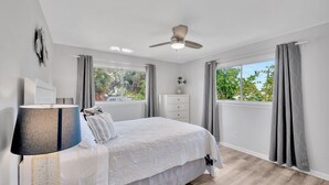 A bedroom with a bed, a ceiling fan, a nightstand, a dresser, and a window with curtains. - Awesome Location! ☀Unlimited Sunsets Included☀ (Indian Rocks Beach)
