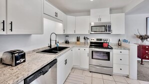 A modern kitchen with white cabinets, a stainless steel microwave, a toaster, and a red kettle. - Awesome Location! ☀Unlimited Sunsets Included☀ (Indian Rocks Beach)