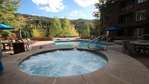A hot tub surrounded by lounge chairs and a pool, with a mountain view in the background. - Buffalo Lodge 8413 (Keystone)