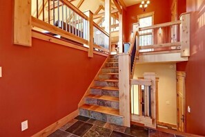 Un escalier avec des rampes en bois et des marches en pierre menant à un palier du deuxième étage.