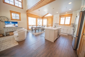 A spacious kitchen with wooden flooring, a dining area with a large table, and a refrigerator. - Settlers Creek 6565 (Keystone)