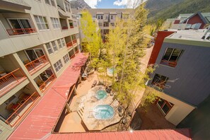 A multi-story building with balconies, a rooftop pool area, and a view of a mountainous landscape. - Silver Mill 8255 (Keystone)
