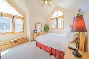 A bedroom with a bed, a dresser, a mirror, a lamp, and a ceiling fan. - Ironwood 2986 by SummitCove Vacation Lodging (Keystone)