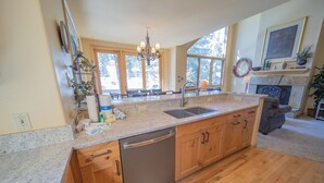 A spacious kitchen with granite countertops, wooden cabinets, a dishwasher, and a large window providing natural light. - Ironwood 2986 by SummitCove Vacation Lodging (Keystone)