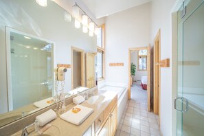 A modern bathroom with a large mirror, dual sinks, and a shower area. - Ironwood 2986 by SummitCove Vacation Lodging (Keystone)