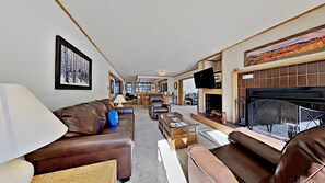 A spacious living room with a fireplace, leather sofas, and a television. - Pines 2086 (Keystone)