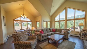 A spacious living room with a high ceiling, large windows, and a cozy seating area. - Gateway Lodge 5089 (Keystone)