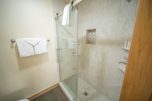 A glass-enclosed shower with a tiled wall and a wooden floor. - Ski Run 411 (Keystone)