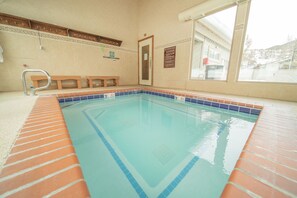 A swimming pool with a tiled edge, benches, a door, and a window with a view. - Flying Dutchman 1164 by SummitCove Vacation Lodging (Keystone)