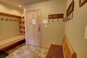 A room with a wooden bench, a door with a sign, a wall-mounted shelf with baskets, and a wall-mounted coat rack. - Flying Dutchman 1164 by SummitCove Vacation Lodging (Keystone)
