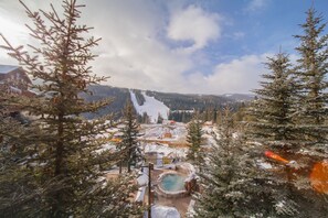 A snowy landscape with a hot spring, pine trees, and a distant mountain range. - Springs 8864 (Keystone)