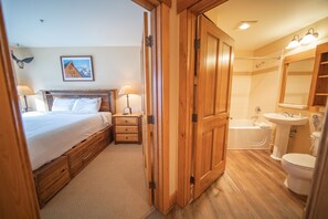 A bedroom with a wooden bed, bedside tables, and a nightstand. The room has a wooden floor and a carpeted area. - Springs 8864 (Keystone)