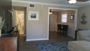 A living room with a sofa, a coffee table, and a patterned rug. There is a dining area with a table and chairs. - Beach Block Bungalow, everything you need for a great get away Quiet and safe (Pompano Beach)
