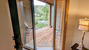 Ein Zimmer mit einer Schiebetür und Glasfront, das auf eine Terrasse mit Blick ins bewaldete Gebiet führt.