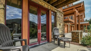 A lodge with a stone facade, large glass doors, and outdoor seating with Adirondack chairs.