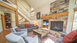 A spacious living room with a fireplace, a staircase, and a bookshelf. - Starfire 1979 (Keystone)