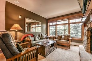 A cozy living room with a fireplace, large windows, and a comfortable seating area.