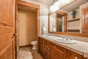 A bathroom with wooden cabinets, a double sink, and a large mirror.