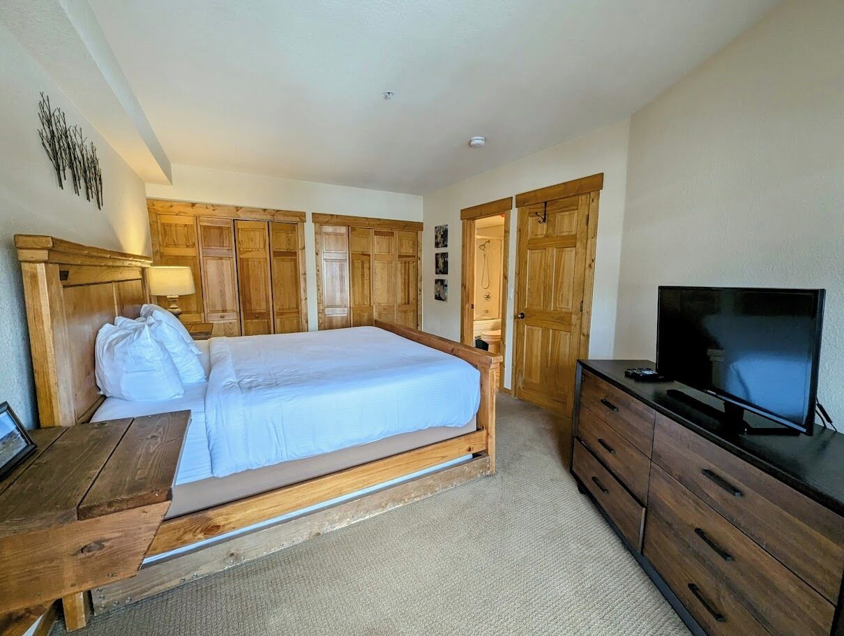 Une chambre à coucher avec un lit en bois, une télévision et une commode.
