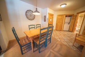 A dining area with a wooden table and chairs, a pendant light, and a patterned floor. - Tenderfoot Lodge 2643 (Keystone)