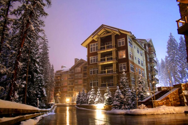 Ein mehrstöckiges Hotel mit einem zentralen Innenhof, umgeben von schneebedeckten Bäumen.