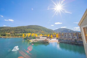 A lakeside view with a dock, buildings, and a mountainous backdrop. - Lakeside 1495 by SummitCove Vacation Lodging (Keystone)
