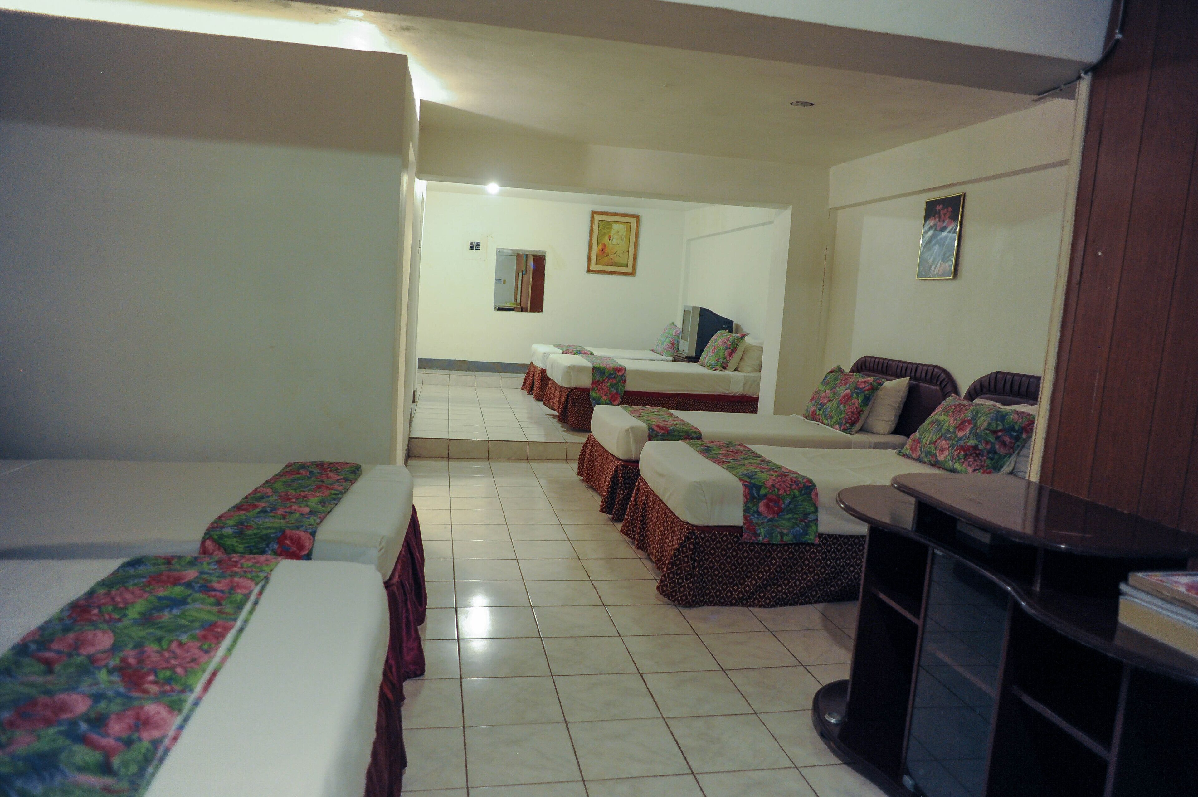A hotel room with multiple beds, a television, and a small table.