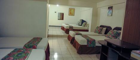 A hotel room with multiple beds, a television, and a small table.