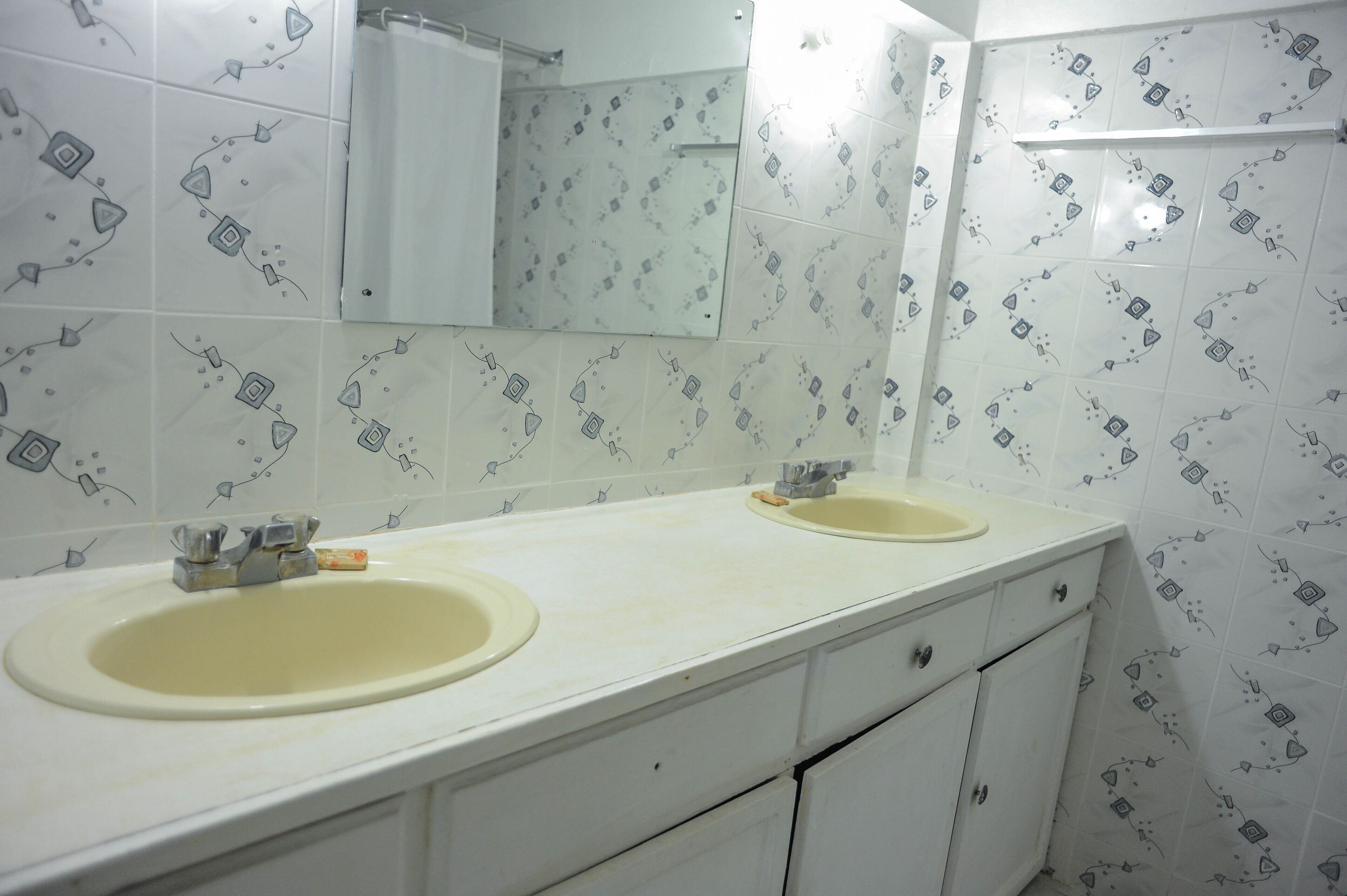 Un baño con dos lavamanos, un espejo y baldosas estampadas.
