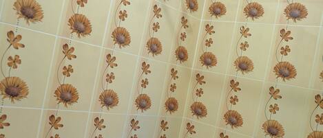 A bathroom with a floral tile pattern, a bathtub, a toilet, and a shower area.