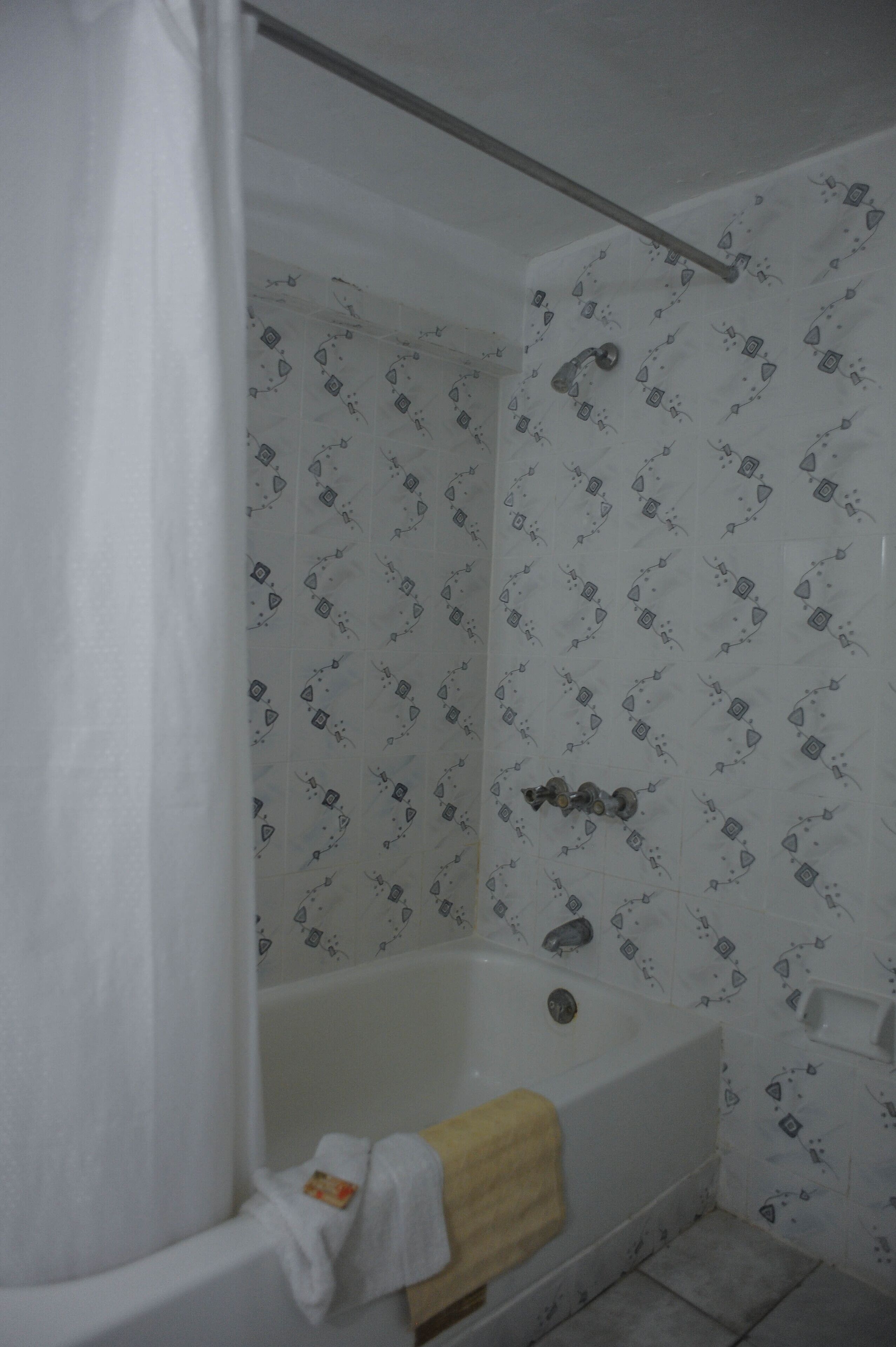 A bathroom with a bathtub, a shower curtain, and patterned wallpaper.